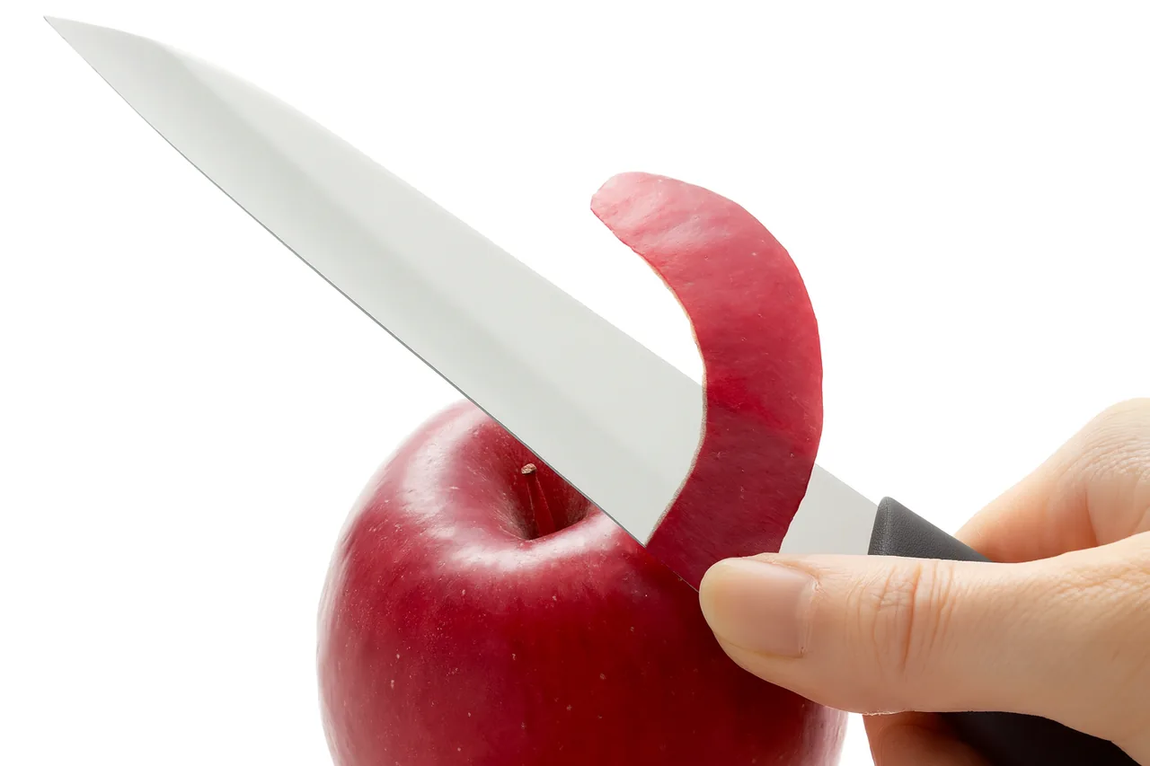 Japanese petty knife used for peeling, demonstrating the compact blade's role in precision kitchen tasks