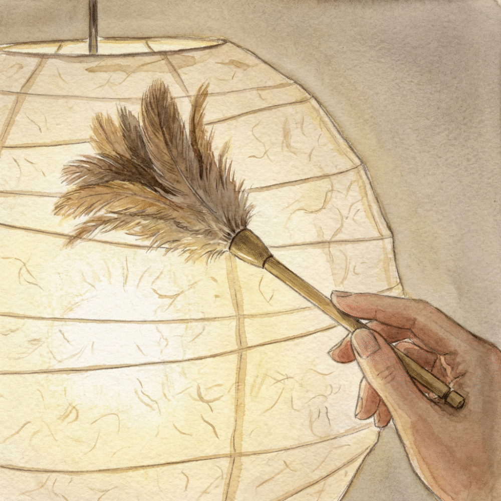 Hands gently dusting a washi floor lamp with a soft brush