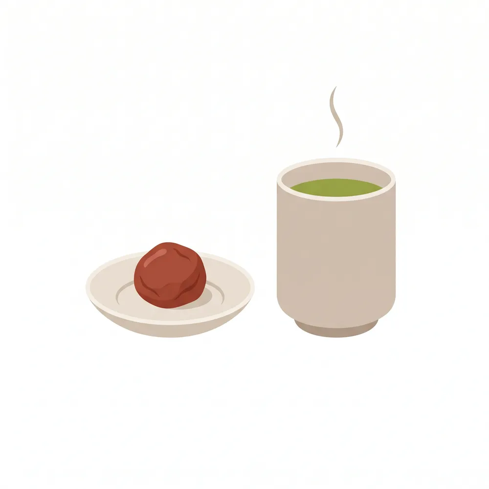 A single umeboshi served with a bowl of plain white rice and a cup of hot green tea, showing the traditional pairings