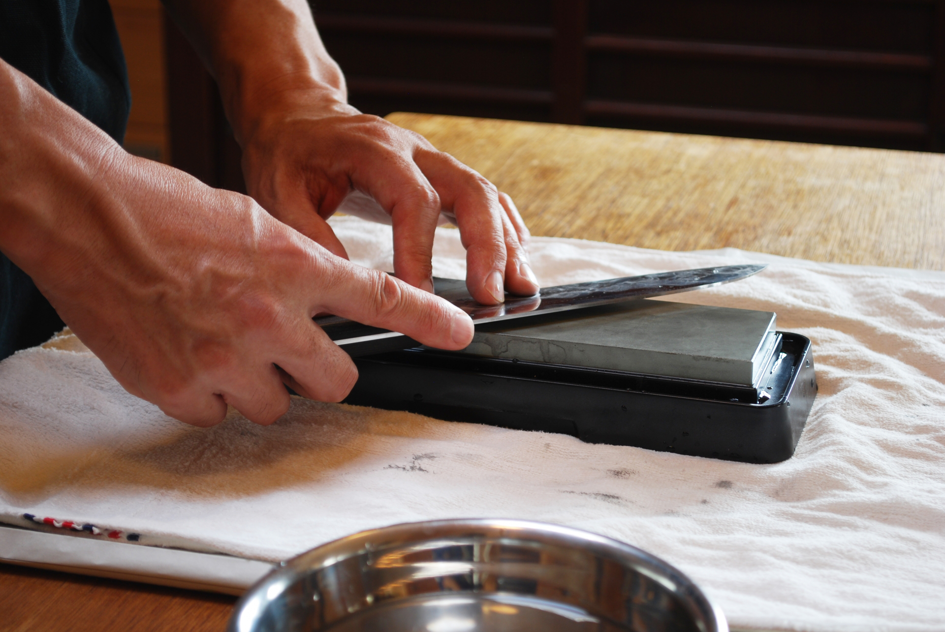 牛刀の刃先を砥石で研いでいる様子