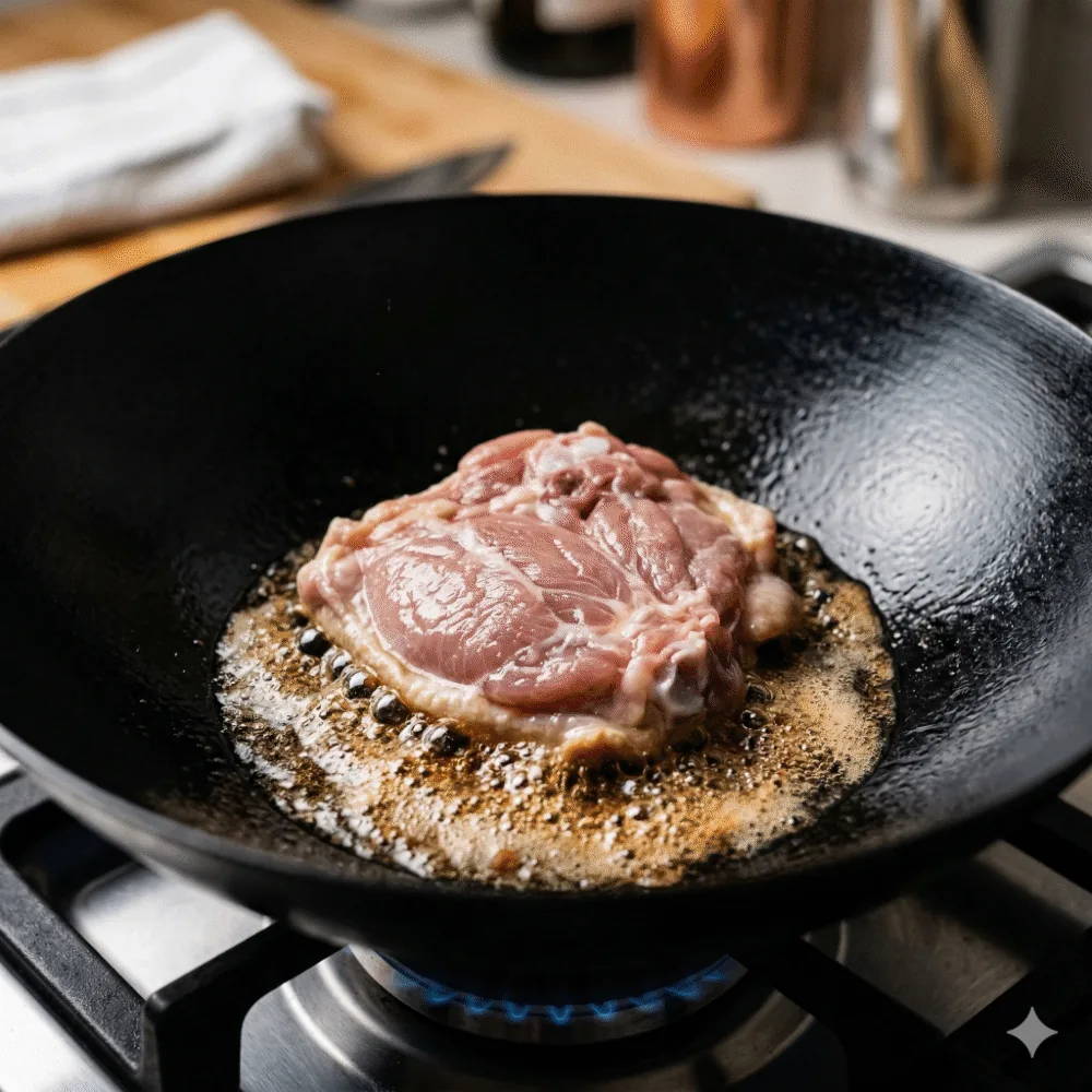 📸 【STEP2画像】フライパンに鶏肉を皮目から入れた瞬間。まだ生肉感が残り、ジュワッという音が聞こえてきそうな写真